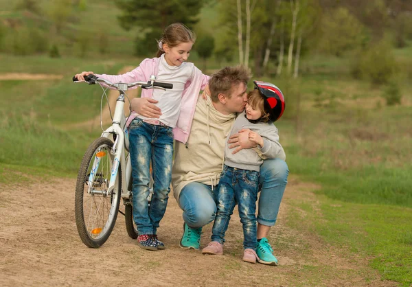 Två små flickor med far embracing utanför — Stockfoto
