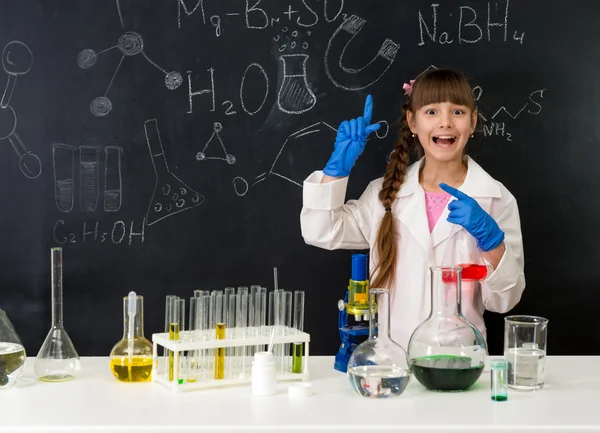 Colegiala en laboratorio de química apuntando a la fórmula en pizarra —  Fotos de Stock