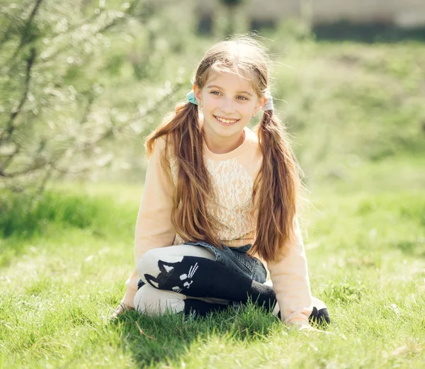 Aranyos mosolygós kislány ül a fűben — Stock Fotó
