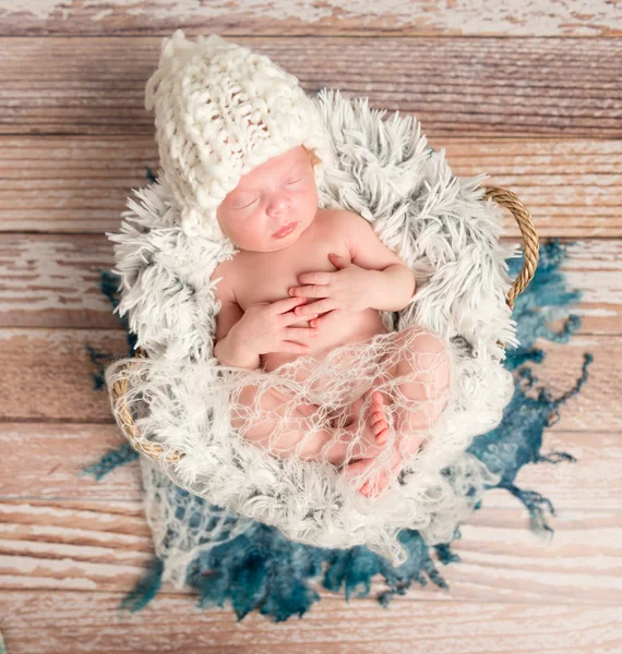 Tiny newborn baby in white knitted hat on fur — Stock Photo, Image