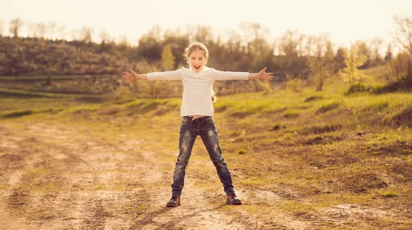 Schattig klein meisje permanent met handen aan zijden op een weg — Stockfoto