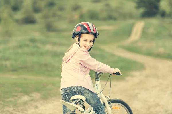 Sorridente bambina in sella a una bicicletta si voltò — Foto Stock