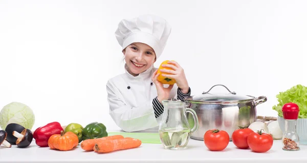 Little girl-cook by table with vegetables — Stock Image Little girl-cook by table with vegetables Royalty Free Stock Images