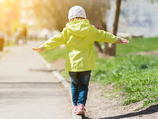 Niña en abrigo amarillo caminando en el parque — Foto de Stock