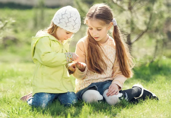 Due bambine giocano sedute su un prato — Foto Stock