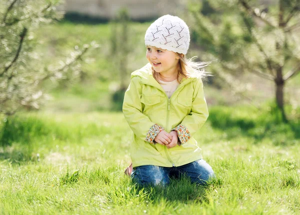 Küçük kız parkta bir Çimenlikte oturan gülümseyen — Stok fotoğraf