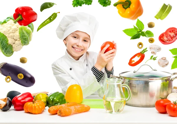 Menina-cozinheiro por mesa com legumes voadores — Fotografia de Stock