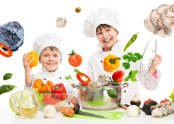 Pequenos chefs por mesa com legumes voadores — Fotografia de Stock