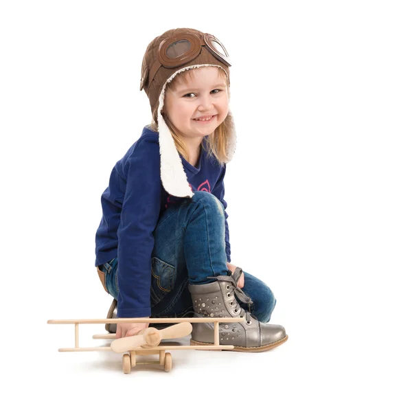 Χαριτωμένο μικρό κορίτσι στο πιλοτικό καπέλο με ξύλινα αεροπλάνο — Φωτογραφία Αρχείου