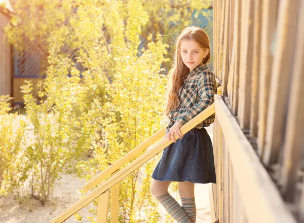 Hermosa niña en las escaleras de la casa de madera — Foto de Stock
