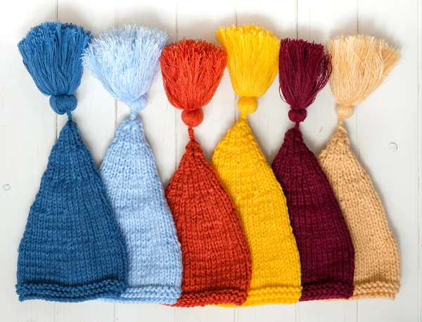 Colorful baby knitted hats folded in row on table — Stok fotoğraf