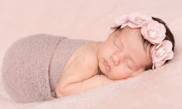 newborngirl sleeping on a pink background