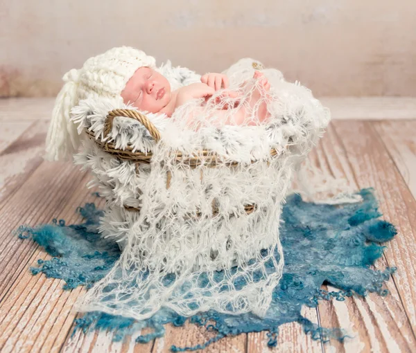 Tiny newborn baby in white knitted hat on fur — Stock Photo, Image