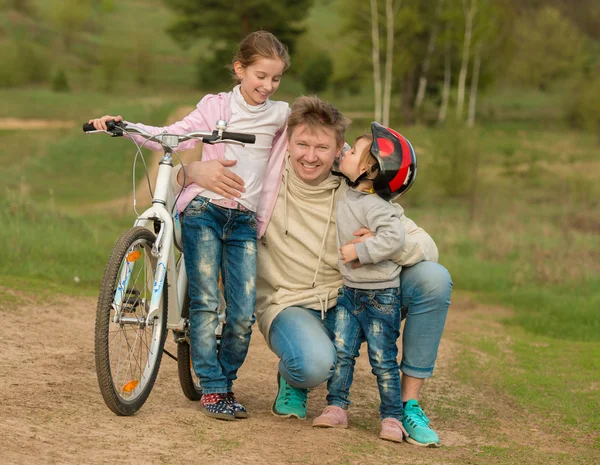 Due piccole figlie che baciano il padre in una passeggiata in campagna — Foto Stock