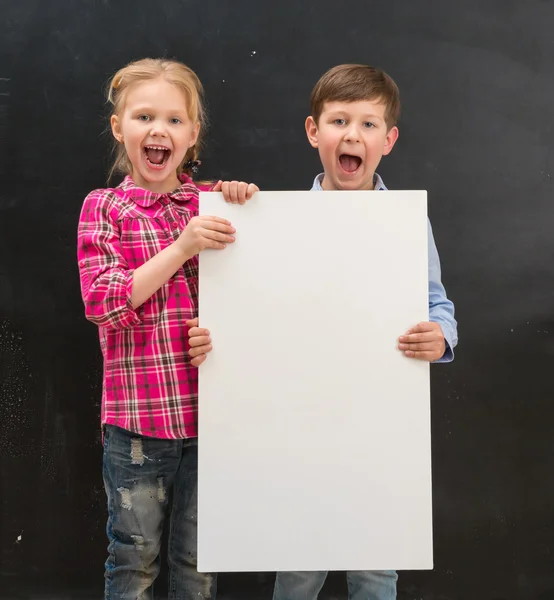 Dos escolares sonrientes con hoja de papel en blanco — Foto de Stock