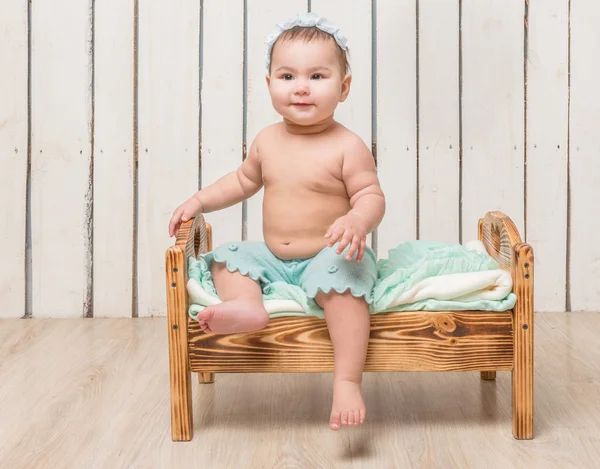 Niño pequeño y juguetón sentado en una cuna — Foto de Stock