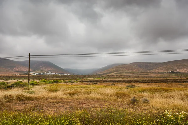 Campos con líneas viales y eléctricas y montañas en Lanzarote — Foto de Stock