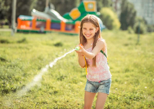 Pequena menina alegre com arma de água — Fotografia de Stock