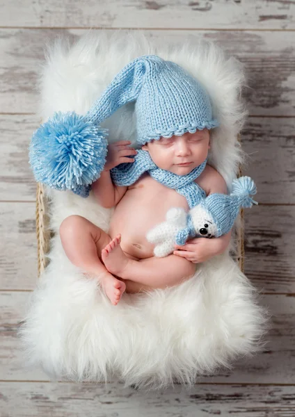 Schönes schlafendes Baby in Hut mit großem Bommel auf flauschigem Kinderbett — Stockfoto