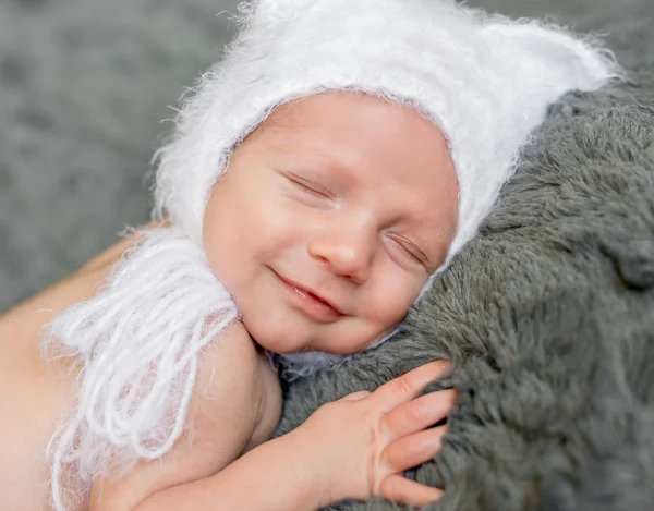 Bambino sorridente in cappello che dorme sulla coperta grigia — Foto Stock