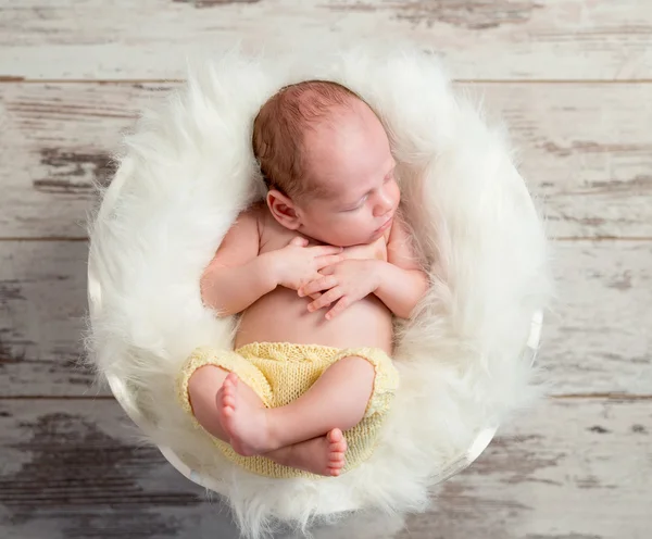 Funny sleepy baby in round cot with legs up — Stock Photo, Image