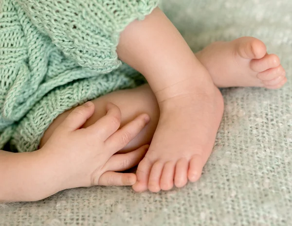 Adorável cruzou pernas de bebê e mão sobre eles — Fotografia de Stock