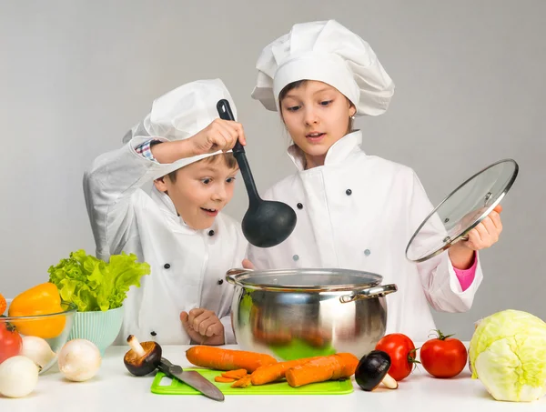Cucinare bambino e ragazza guardando in padella — Foto Stock