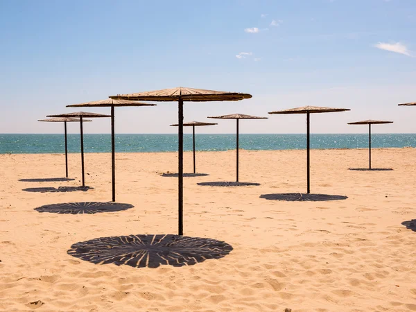 Sombrillas de madera en una playa vacía —  Fotos de Stock