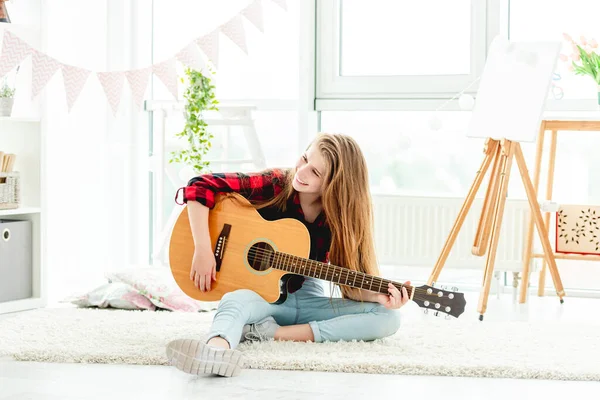 Bella ragazza che suona la chitarra seduta sul pavimento — Foto Stock