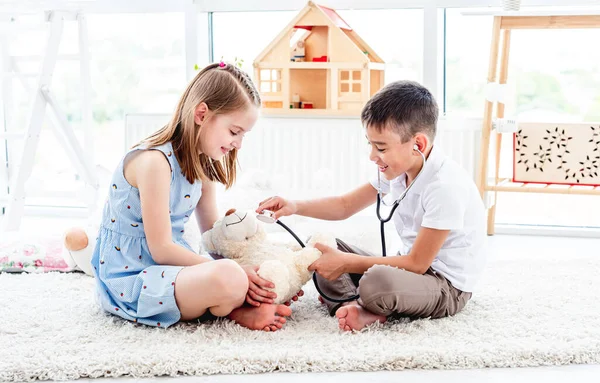 Kinderen doktertje spelen met teddybeer — Stockfoto