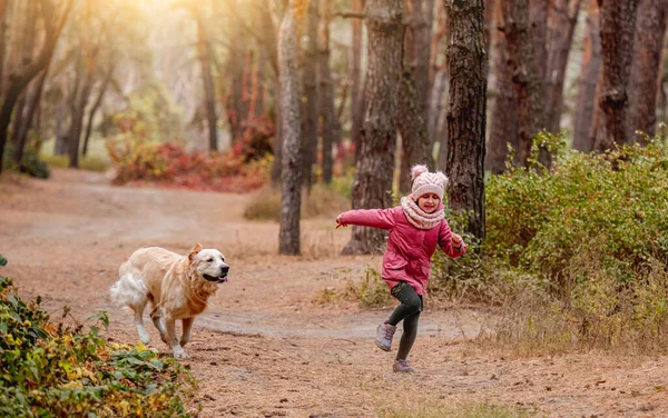 Niña y perro corriendo en madera —  Fotos de Stock