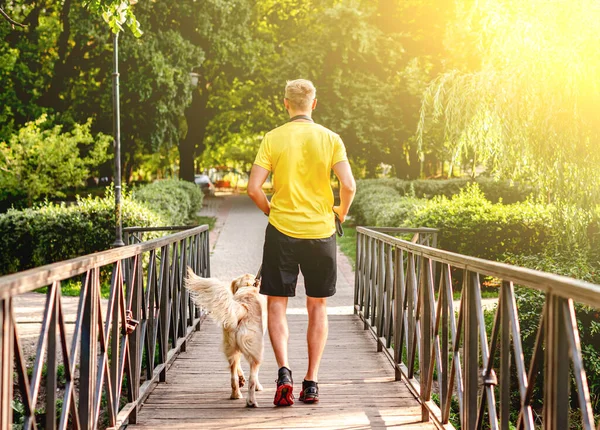 Man joggar över bron med hund — Stockfoto