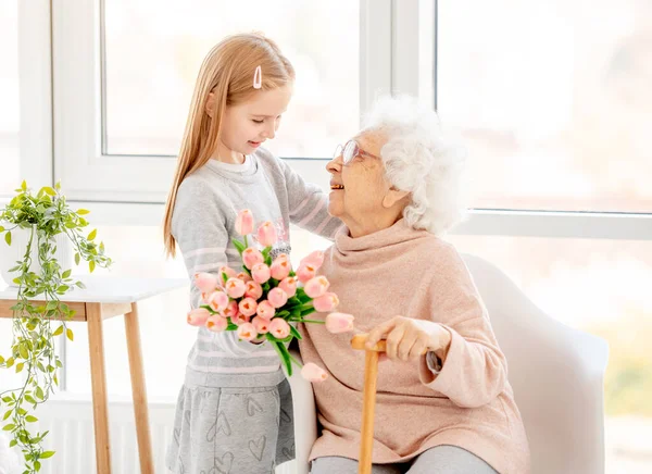 Mädchen überreicht Strauß an alte Frau — Stockfoto