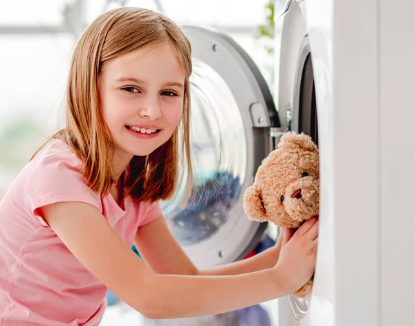 Menina colocando brinquedo na máquina de lavar roupa — Fotografia de Stock