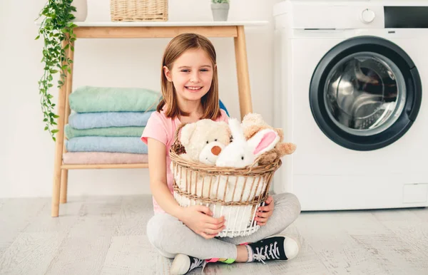Niña sosteniendo juguetes en la cesta de lavado — Foto de Stock