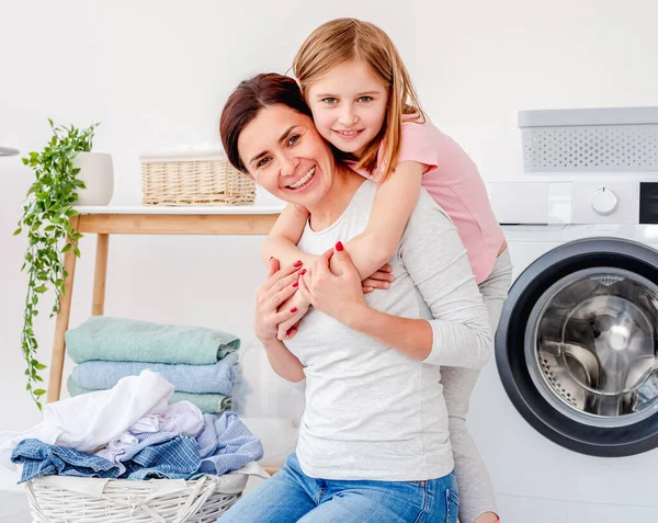Menina abraçando com a mãe durante a lavanderia — Fotografia de Stock