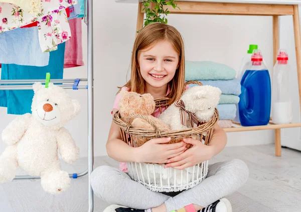 Liten flicka som håller leksaker i tvättkorgen — Stockfoto