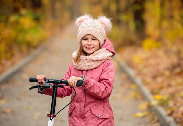 Kleines Mädchen mit Roller steht im Park — Stockfoto