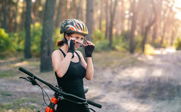 Женщина надевает спортивные очки рядом с велосипедом — стоковое фото