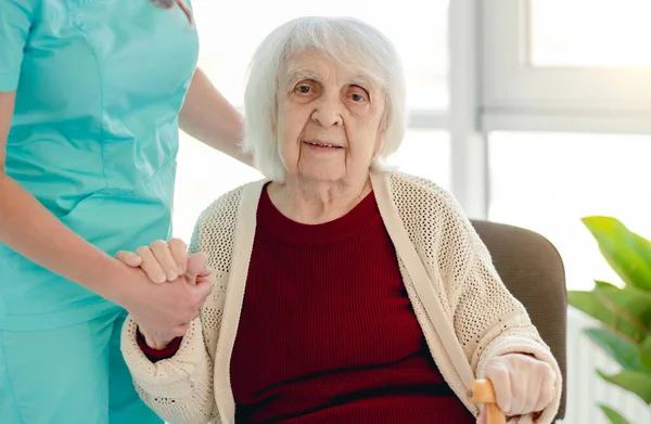Anciana apoyada en la mano de enfermera — Foto de Stock