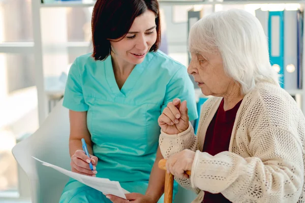 Νοσοκόμα μιλάει με ηλικιωμένη γυναίκα ασθενή — Φωτογραφία Αρχείου