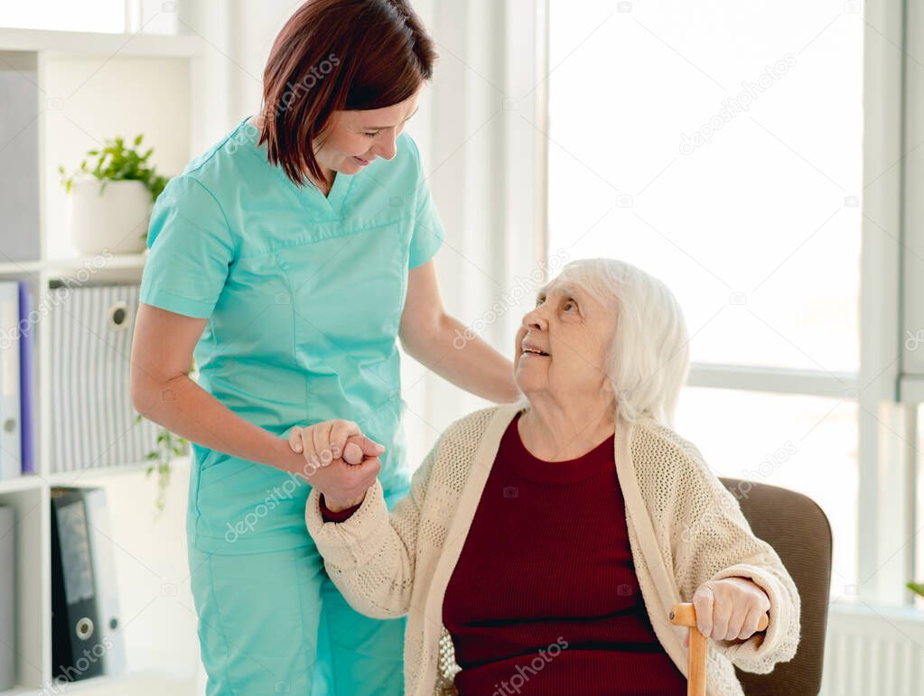 Old lady leaning on nurse hand