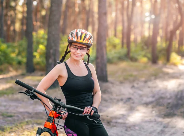 Woman with bike in sunny forest — Stock Photo, Image