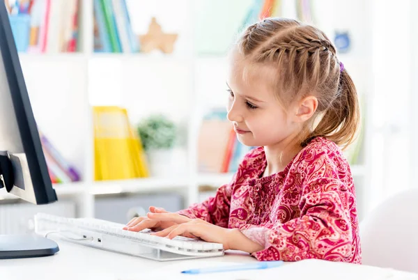 Klein meisje typen op computer toetsenbord — Stockfoto