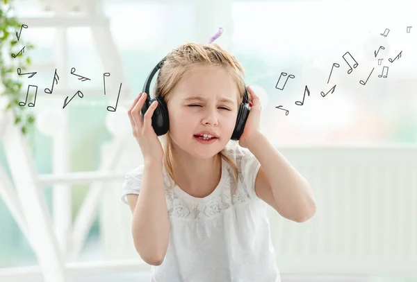 Маленькая девочка слушает музыку в наушниках — стоковое фото
