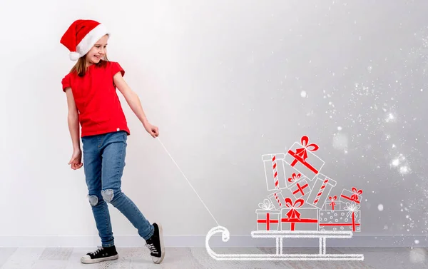 Маленькая девочка тянет сани с рождественскими подарками — стоковое фото