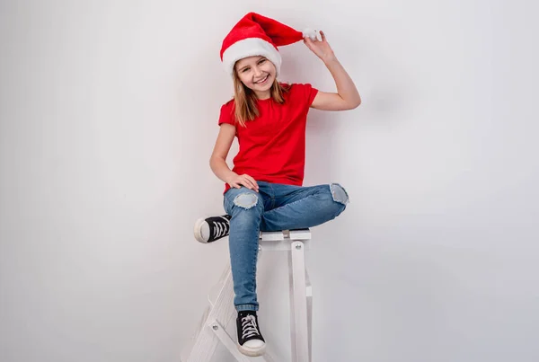 Merdivendeki Noel Baba şapkalı küçük kız. — Stok fotoğraf