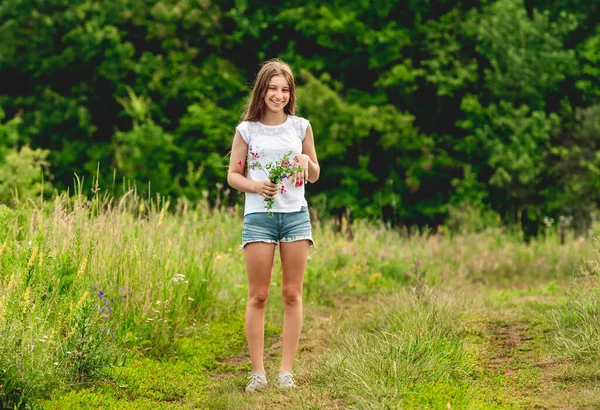 Улыбающаяся девушка с букетом полевых цветов — стоковое фото
