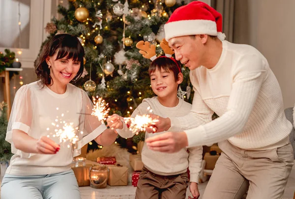 Lycklig familj med tomtebloss under julgranen — Stockfoto