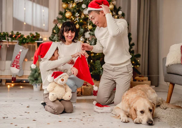 Familia poniendo sombreros de santa cerca del árbol de Navidad —  Fotos de Stock